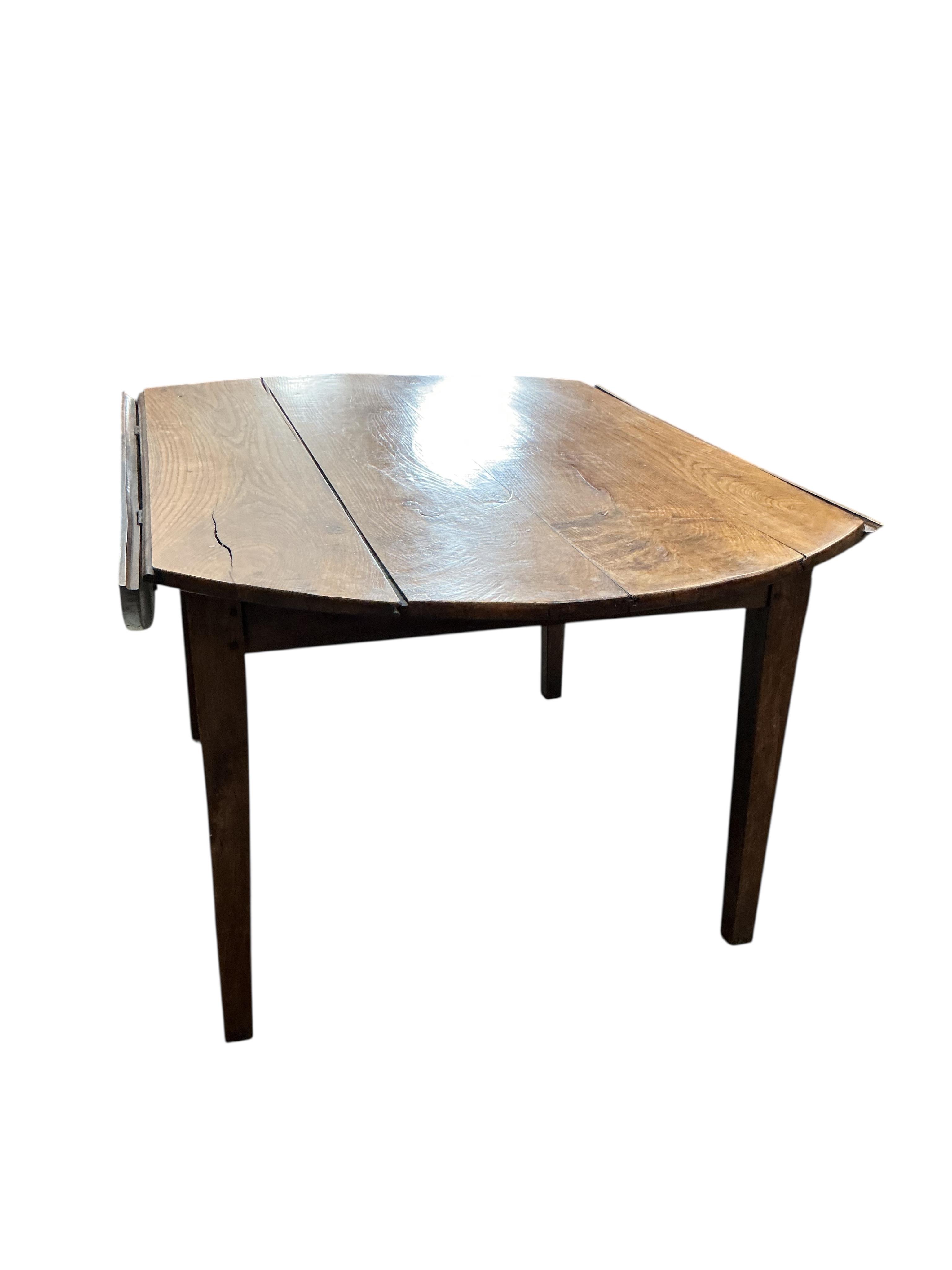 A 19th century French Provincial oak drop leaf dining table, diameter 138cm, extended, height 73cm